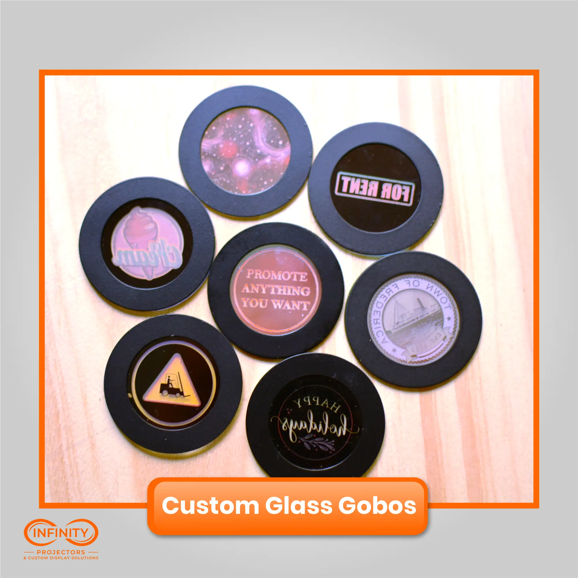 Seven custom glass gobo slides laid on a wood table, mixing text, logos, and full-color artwork