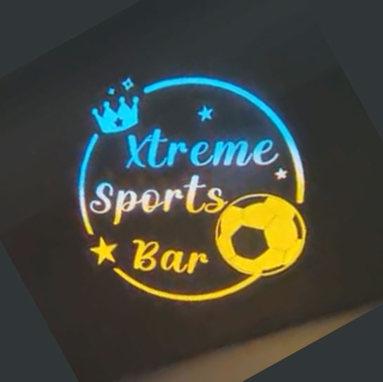Real photo of a full-color gobo projection: sports bar logo with soccer ball in blue and yellow light
