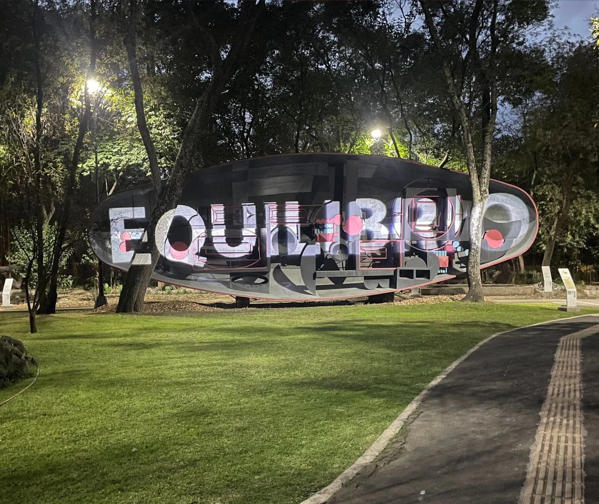 The word EQUILIBRIO projection-mapped across an oval pavilion sculpture in a park at dusk; branded product image