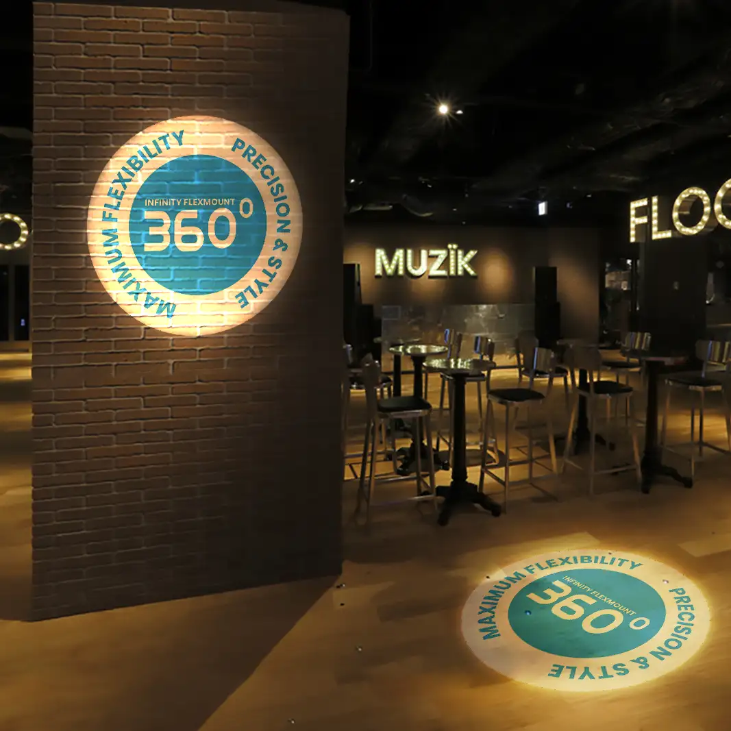 Round 360-degree gobo projected on a brick wall and wood floor of a dimly lit bar with high-top tables
