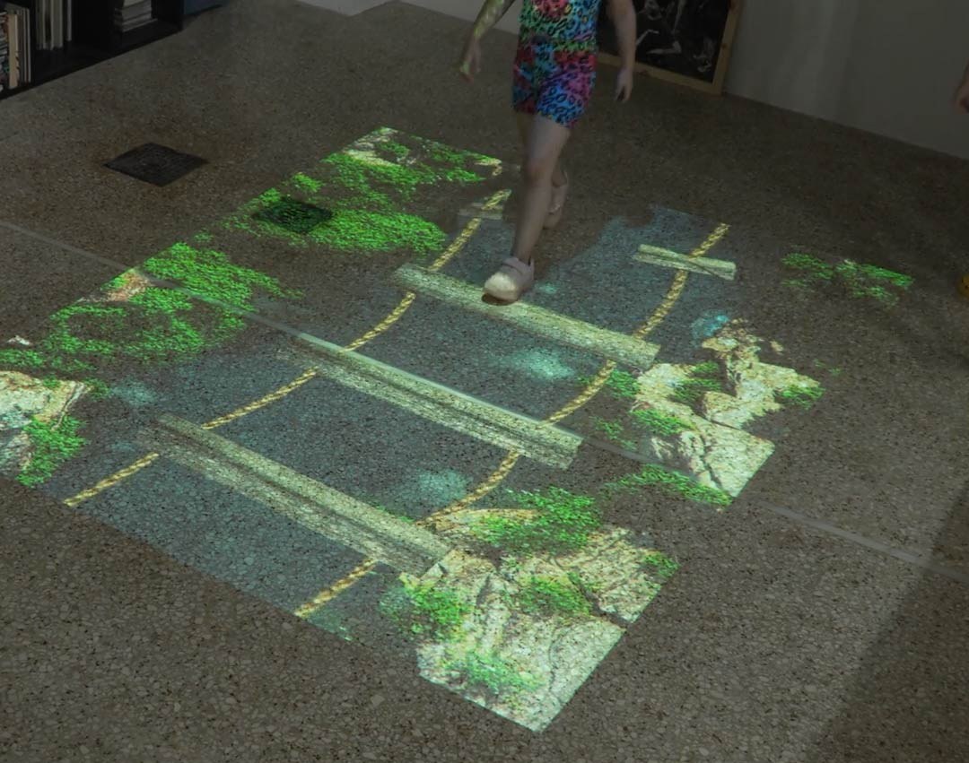 Video: girl steps across a jungle log-bridge obstacle game projected on the floor