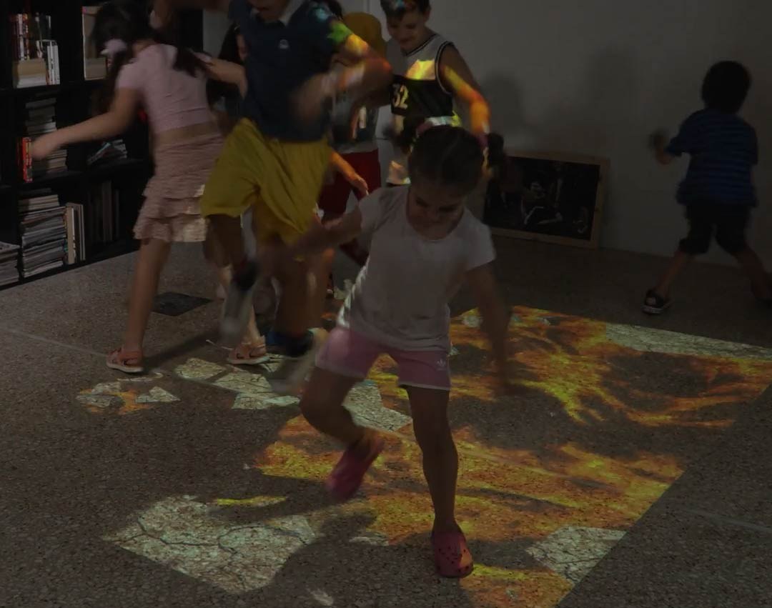 Video: kids stomp glowing lava splashes on an interactive floor game in a playroom