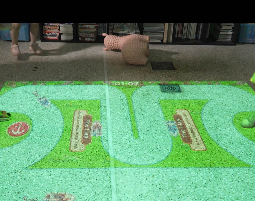Video: winding boat-race track game projected on the floor as kids play along its edges