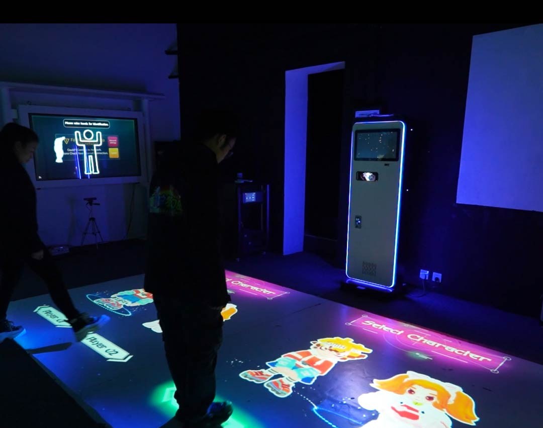 Video: players choose cartoon characters in a select screen projected on the floor of a neon-lit game room