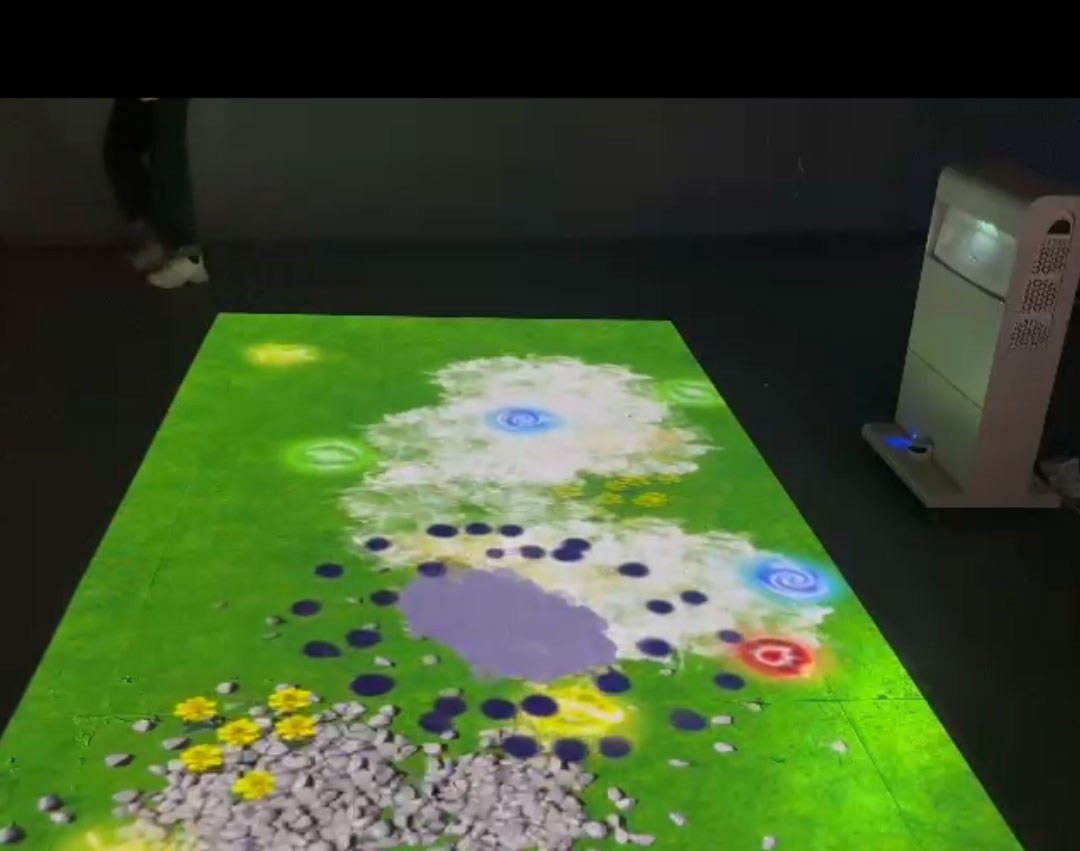 Video: interactive meadow with flowers, pebbles and swirls projected on a play floor, reacting to footsteps