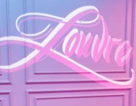 Video: elegant white script name flows across a pink paneled wall in projected light