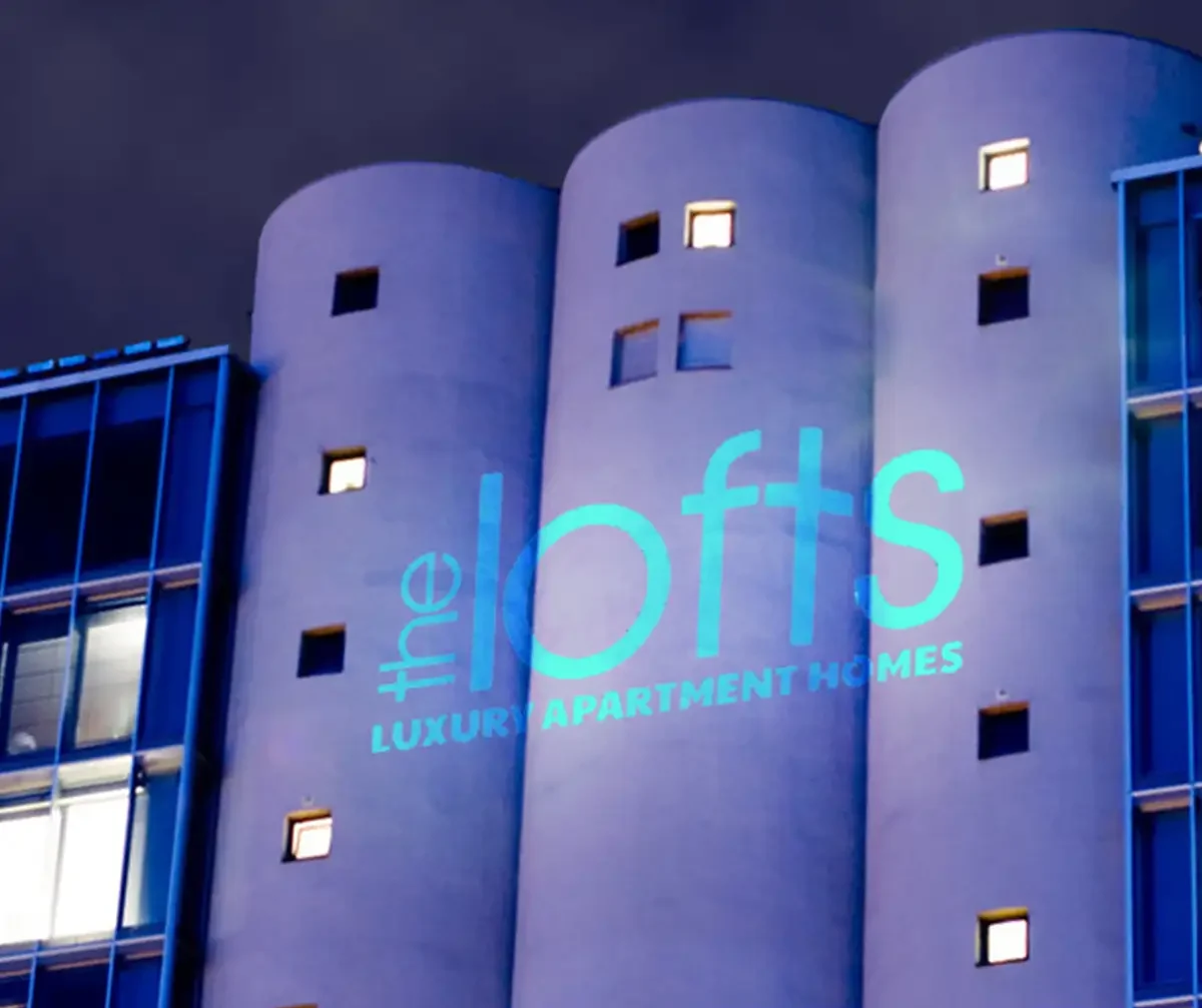 Buildings — Apartment brand wordmark projected large across a building facade at night