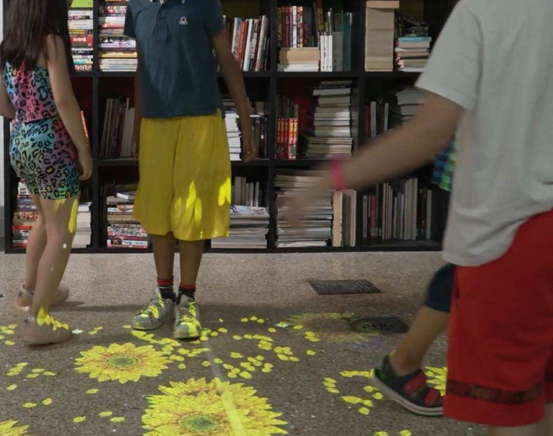 Video: interactive sunflowers bloom and scatter petals underfoot beside library shelves