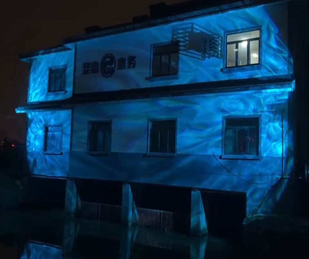 Video: liquid ripple effect rolls across a building facade at night, turning the walls into flowing water