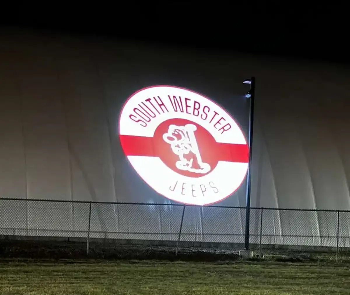Round red and white school spirit crest projected at giant scale on an inflatable sports dome at night — Infinity Projectors