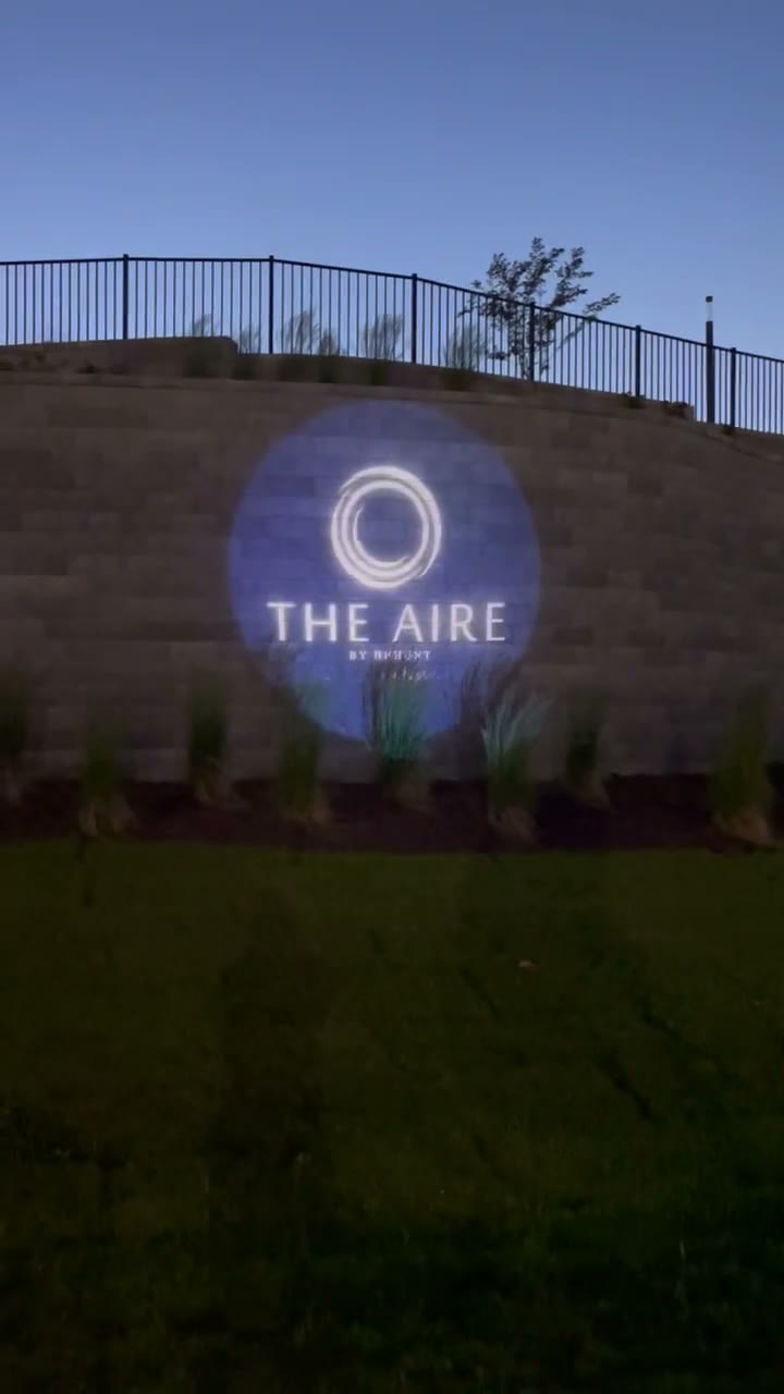 THE AIRE by Bryhunt logo gobo projected on a real retaining wall at dusk — Infinity Projectors