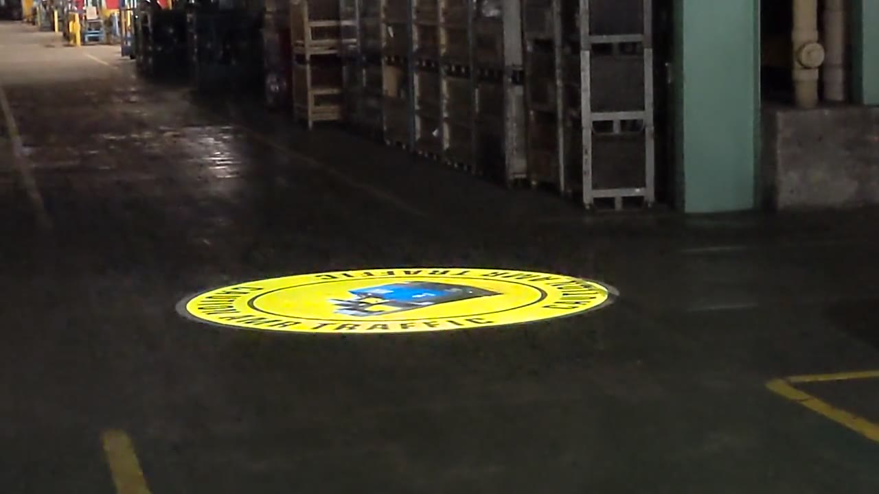 Projected CAUTION AMR TRAFFIC safety sign on a real warehouse floor — Infinity Projectors safety sign projector — Infinity Projectors