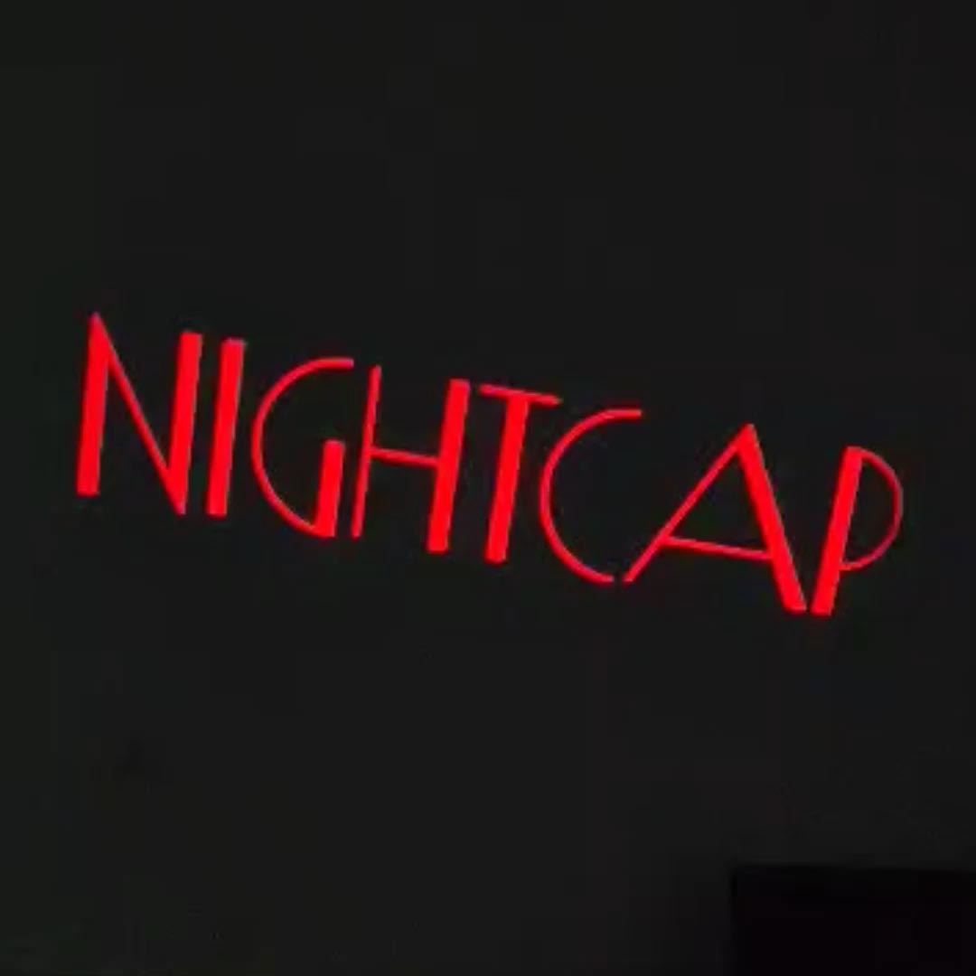Video: red art-deco style bar name lettering projected in crisp light on a dark interior wall