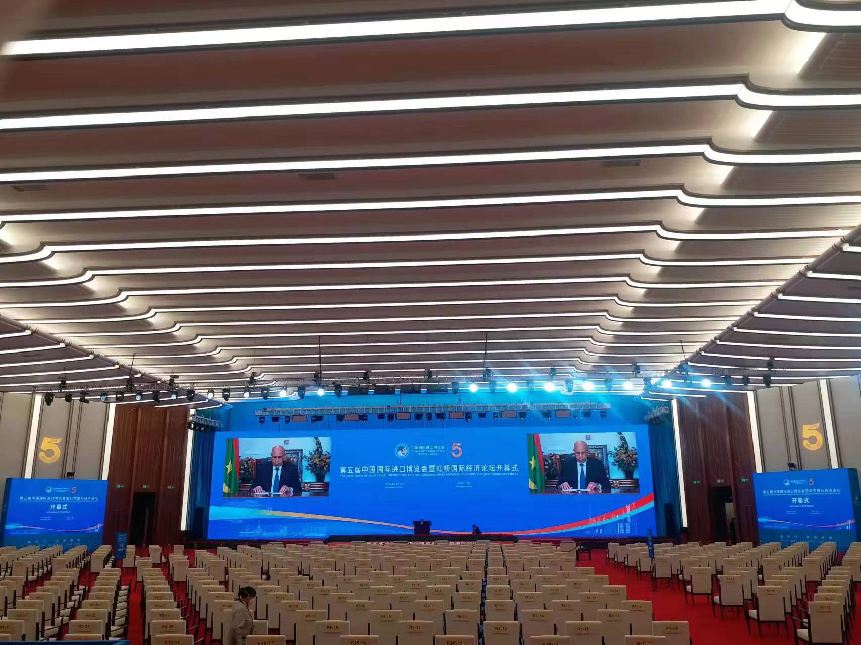 Convention hall with a wide LED stage screen showing a speaker feed at an international expo opening ceremony — Infinity Projectors