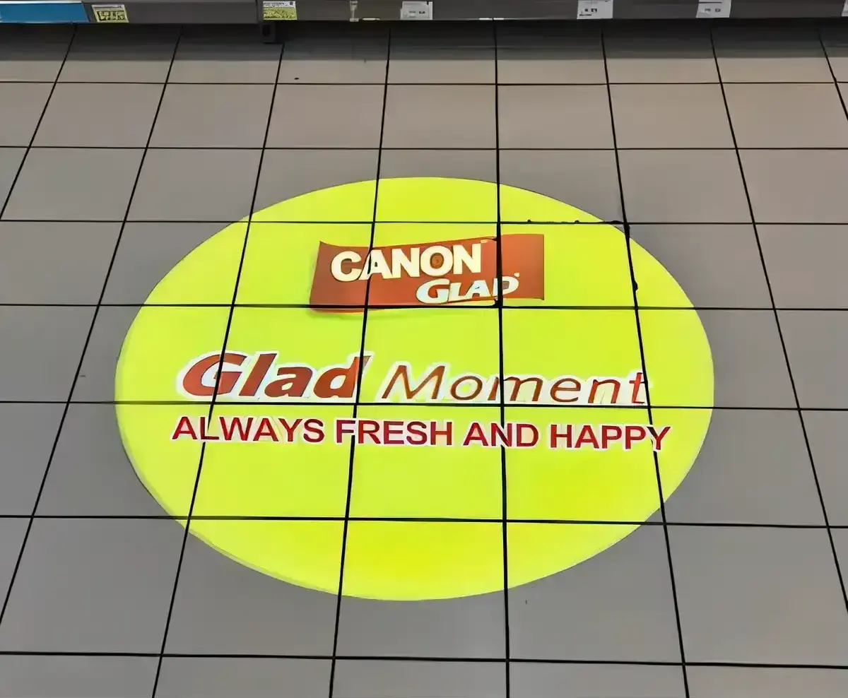 Bright green circle with a grocery promo slogan projected on gray pavement outside a storefront — Infinity Projectors