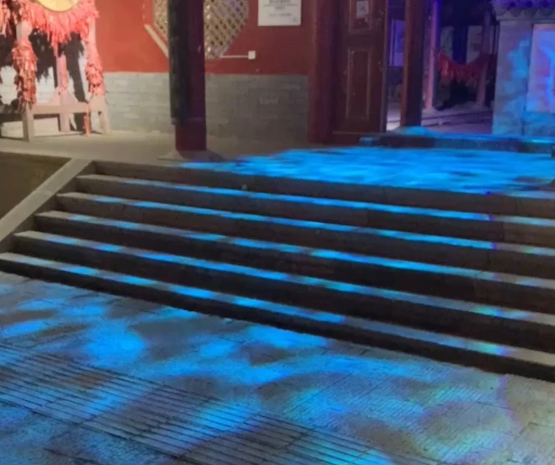 Video: blue water-ripple light washes over stone steps and courtyard pavers at night
