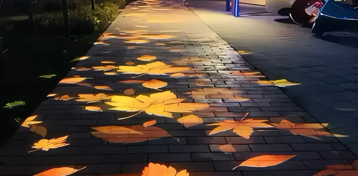 Warm orange maple leaves projected along a brick park path at night near a playground, like fallen autumn light