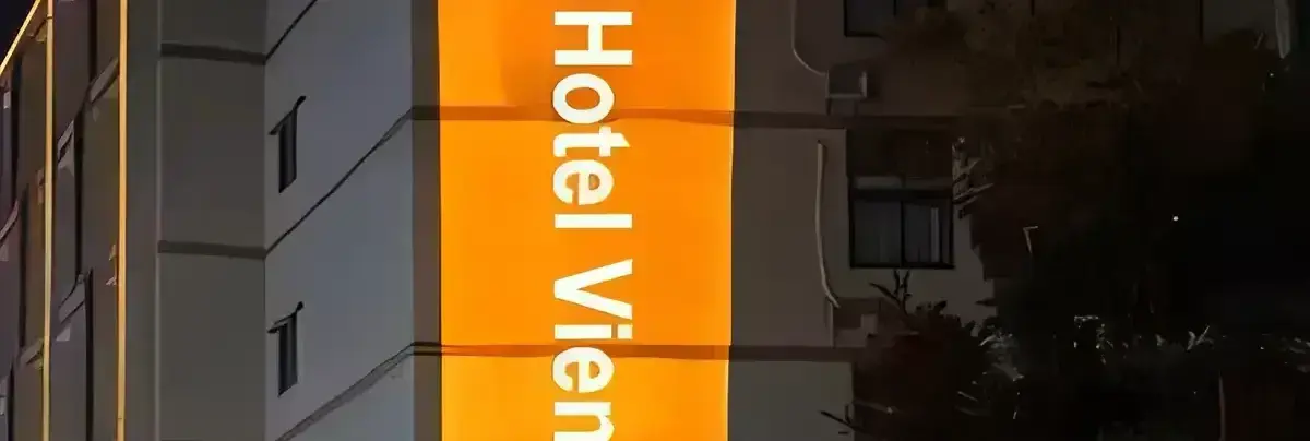 A hotel's name and winged emblem in a tall orange panel of light running down a building corner at night