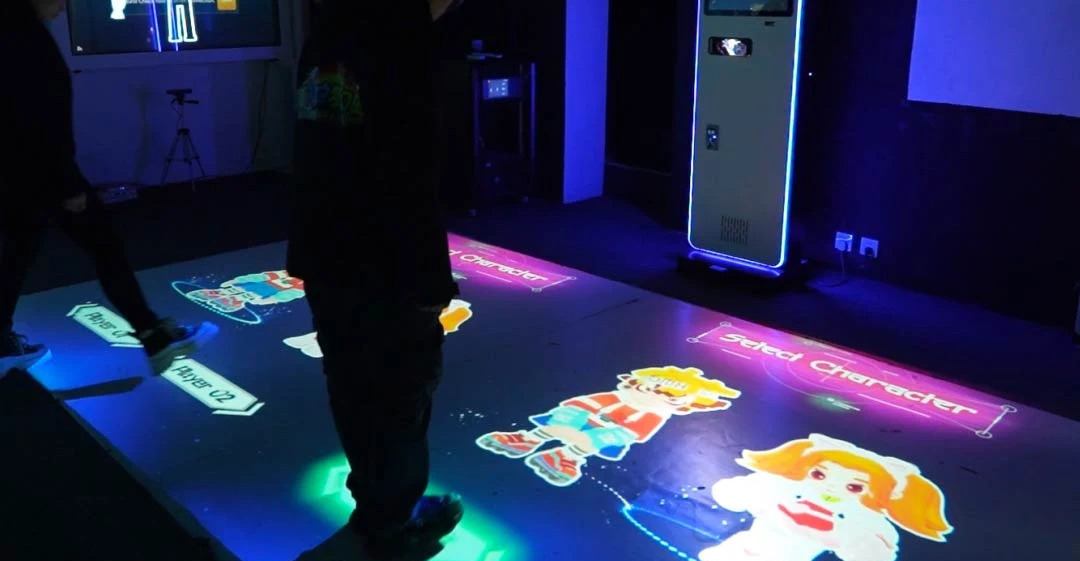 Video: players choose cartoon characters in a select screen projected on the floor of a neon-lit game room
