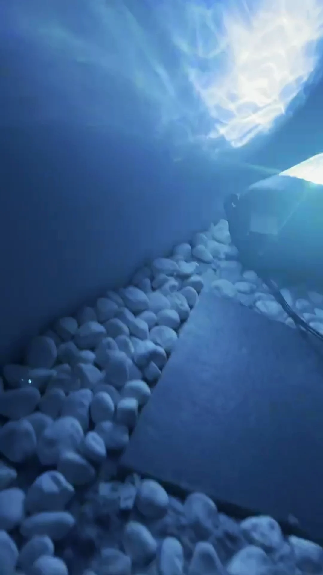 The Aurora on a pebble bed, throwing pale blue waves across a wall and ceiling — Infinity Projectors