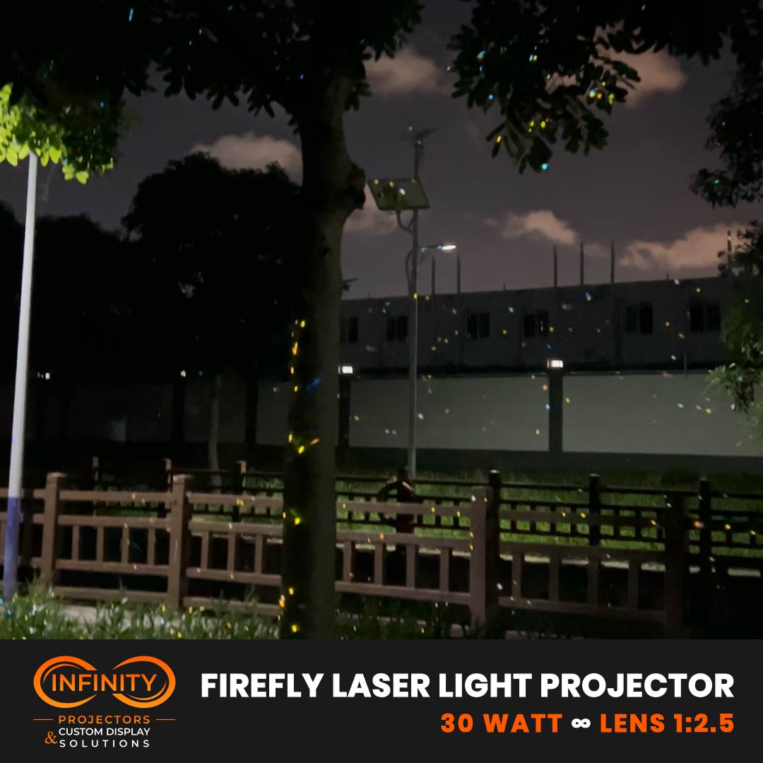 Video: multicolored firefly laser specks drift through trees and fencing in a park at night