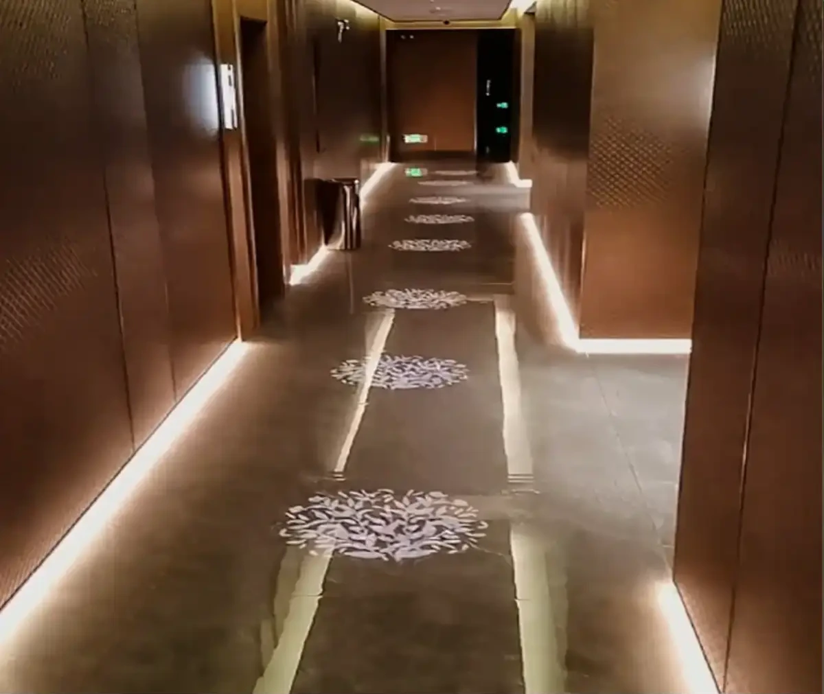 Trail of white foliage motifs projected along a dim hotel corridor's marble floor — Infinity Projectors