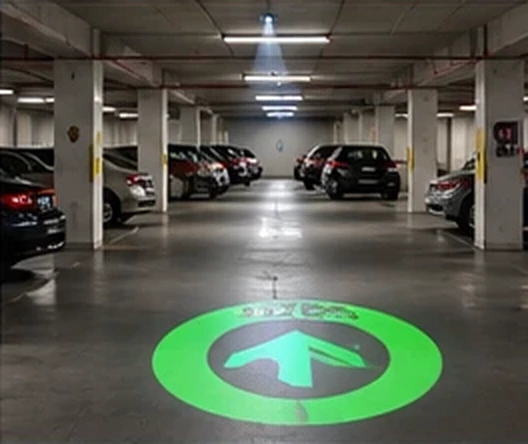 Parking garage with a green arrow disc projected on the deck between parked cars — Infinity Projectors