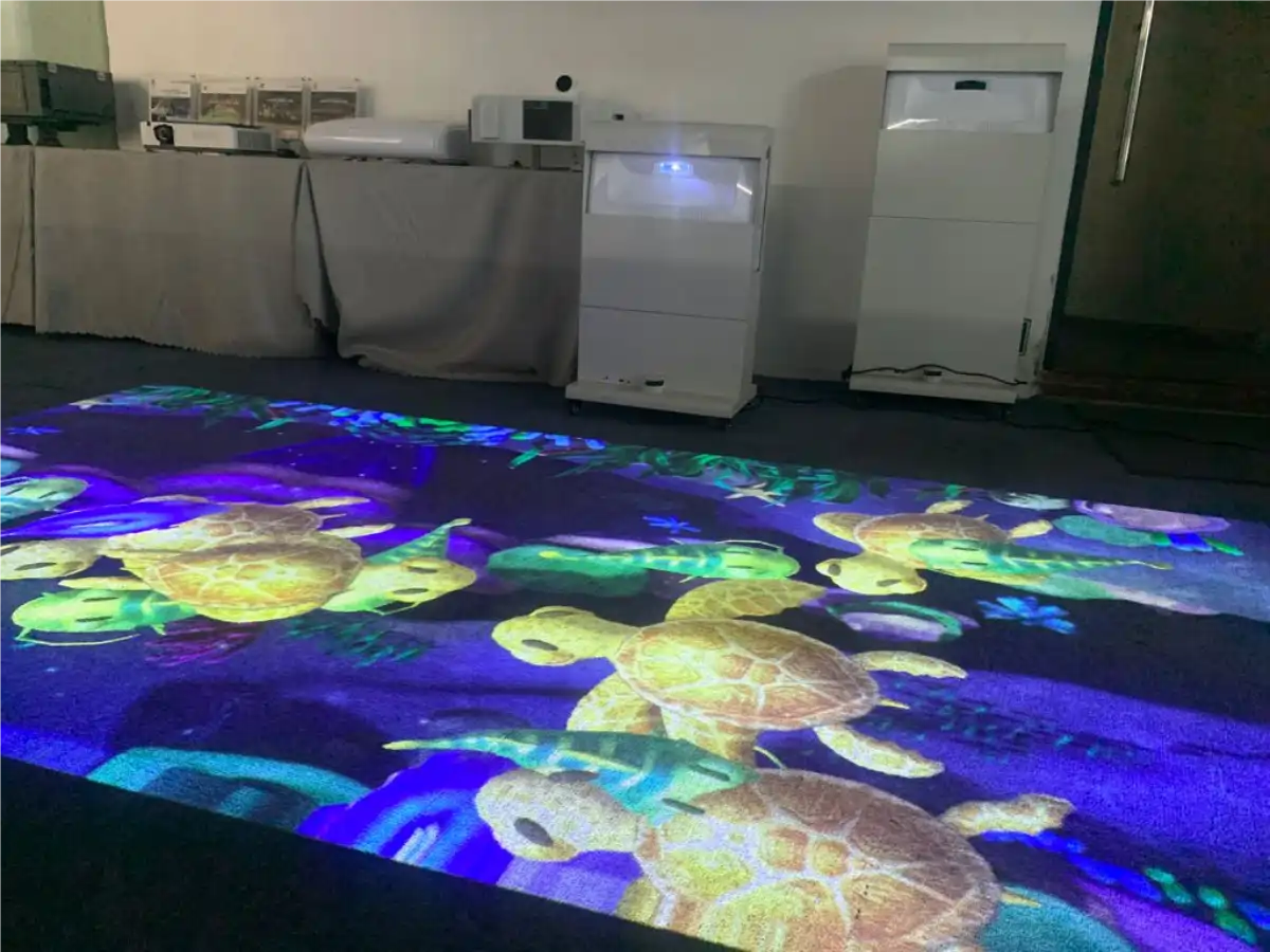 Interactive floor projection of swimming sea turtles — kids play on an underwater scene from an Infinity interactive projector