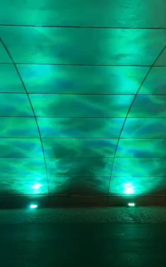 Teal aurora waves projected up the walls and ceiling of a curved tunnel — Infinity Projectors