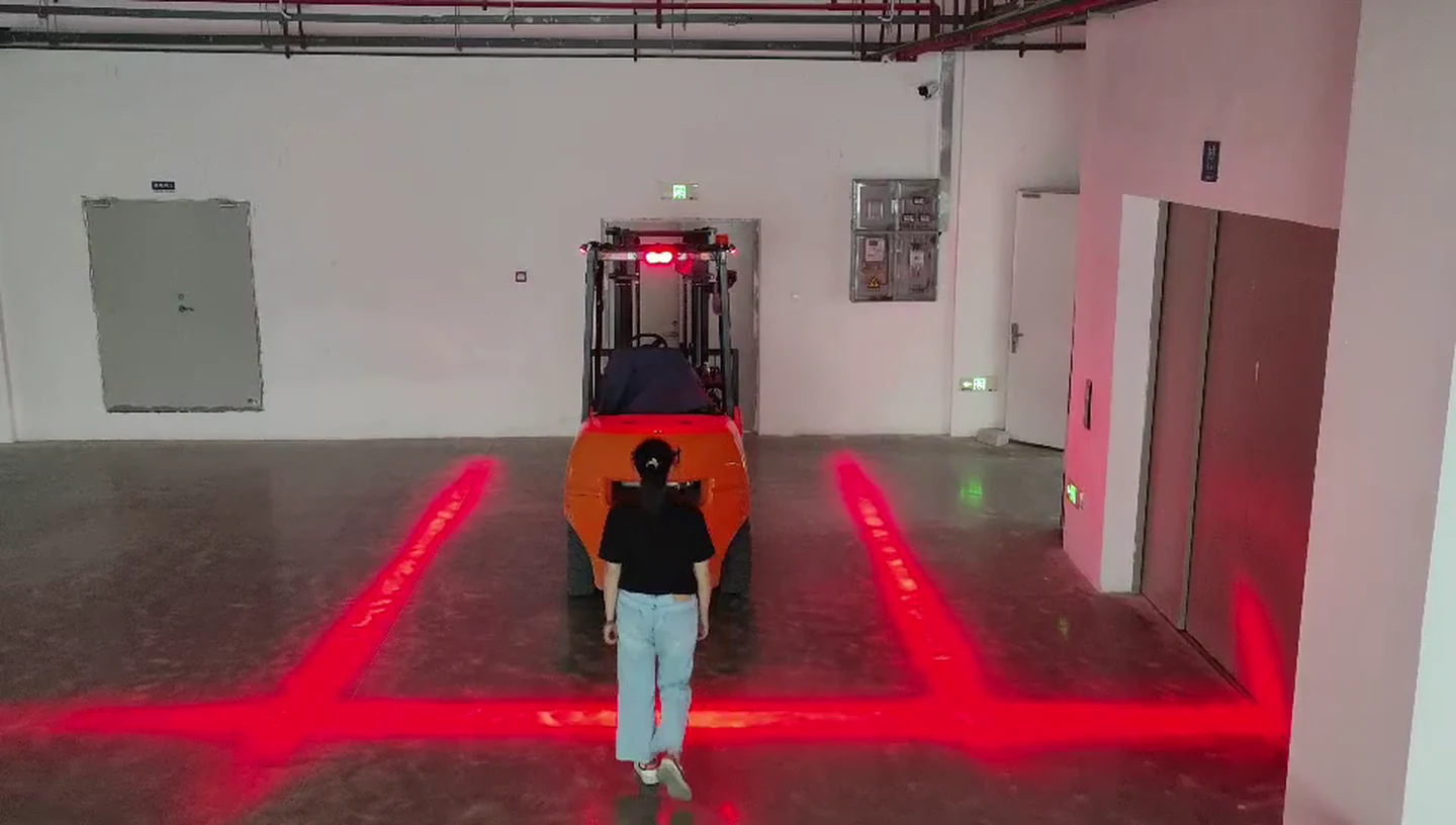A person walking toward a forklift stops at the red rear boundary line projected on the floor, with side lines running along both sides of the truck — Infinity Projectors