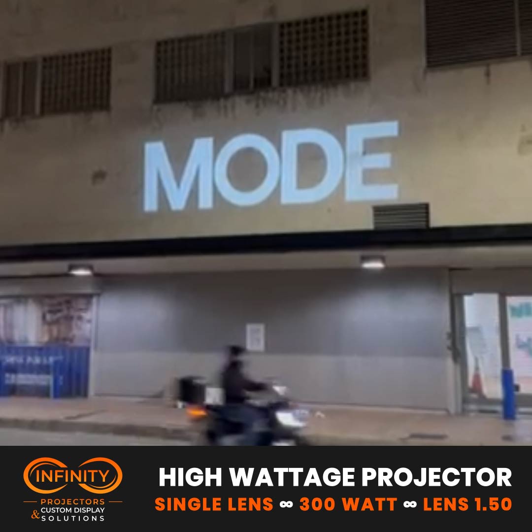 Video: giant white store name projected high on a building facade over a night street
