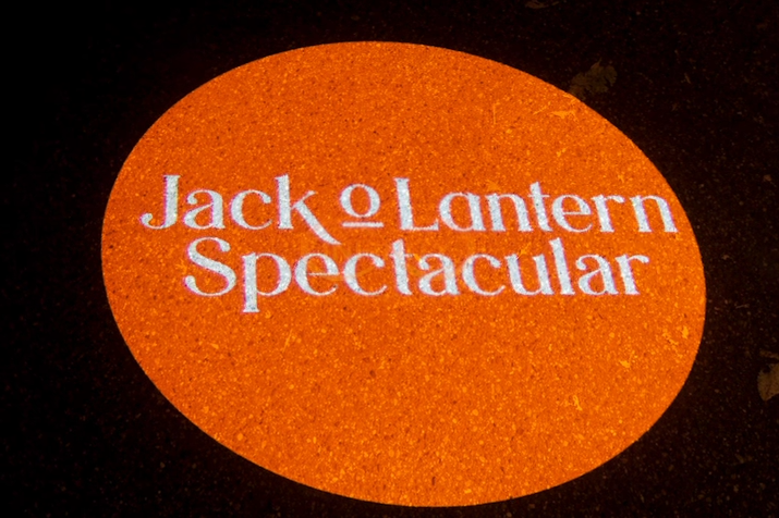 Video: close-up of a white serif event title inside an orange gobo circle on pavement