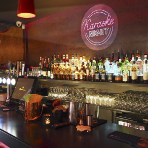 Real photo of Karaoke Night logo projected behind bar — real install