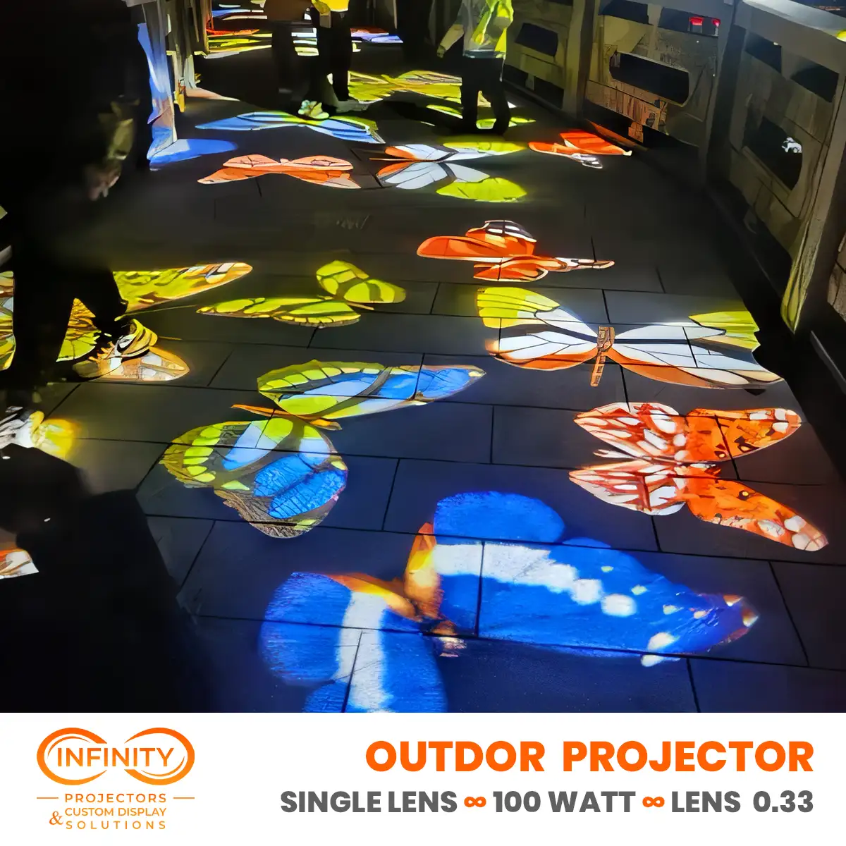 Vivid orange, blue and yellow butterflies projected over dark stone pavers as visitors walk through the gobo light display