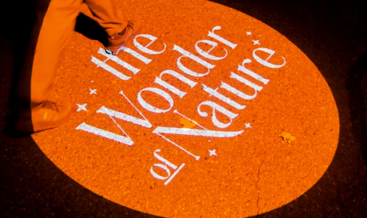 Real photo of text projected on orange circle, hand visible — Infinity Projectors